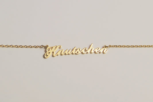 Goldfarbene Kette mit dem Schriftzug Knutschen