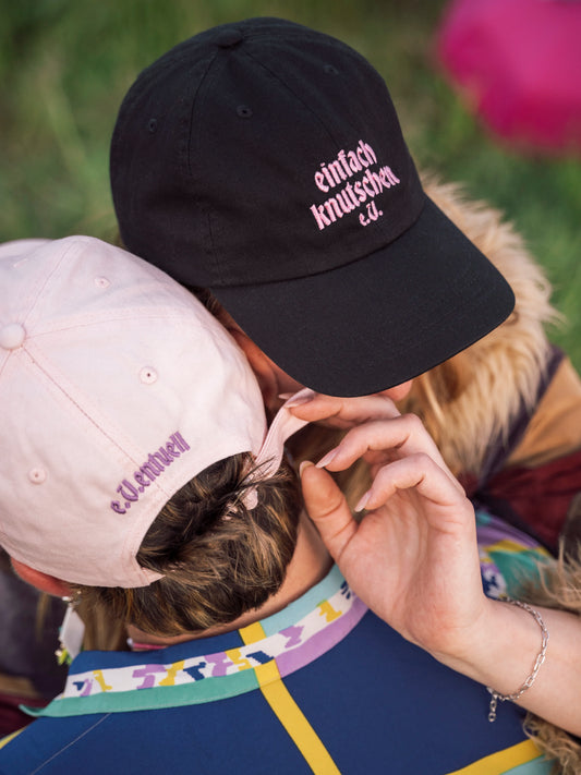 Zwei Menschen küssen sich mit Caps „einfach knutschen e.V.“ – Symbol für Nähe und Offenheit.