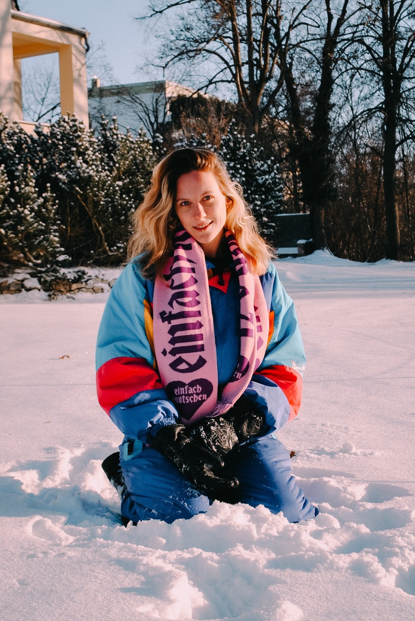 Einfach Knutschen Fanschal in risa mit lila Schriftzug, getragen von einer Person im Schnee – Winter-Fanschals mit auffälligem Branding von einfach knutschen.
